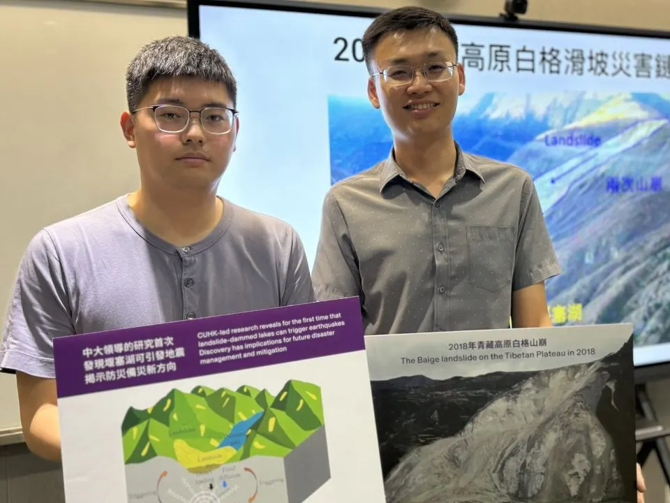 Professor Yen Joe Tan (right) and Dr Liu Min (left) holding posters of the study, in front of a screen showing the 2018 Baige landslide on the Tibetan Plateau.