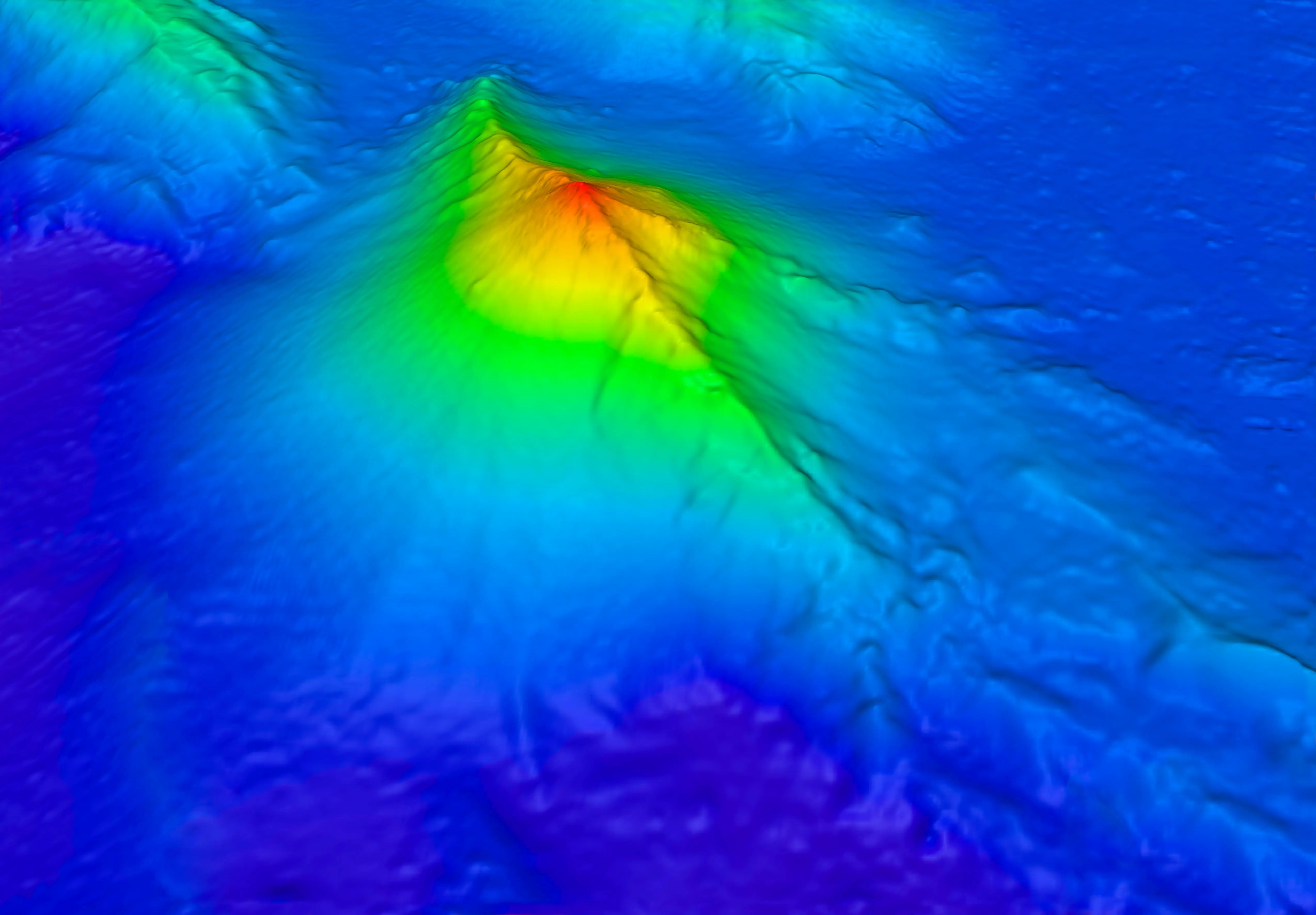 Colour-coded sonar relief map of the West Mata undersea volcano, its ridged summit rising in red and yellow out of the deep blue seafloor.